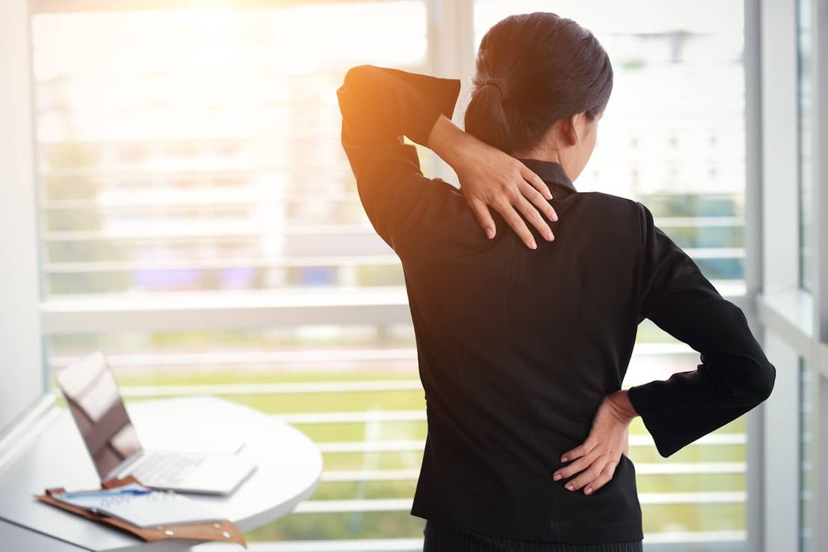Woman holding attempting to hold her mid back due to pain