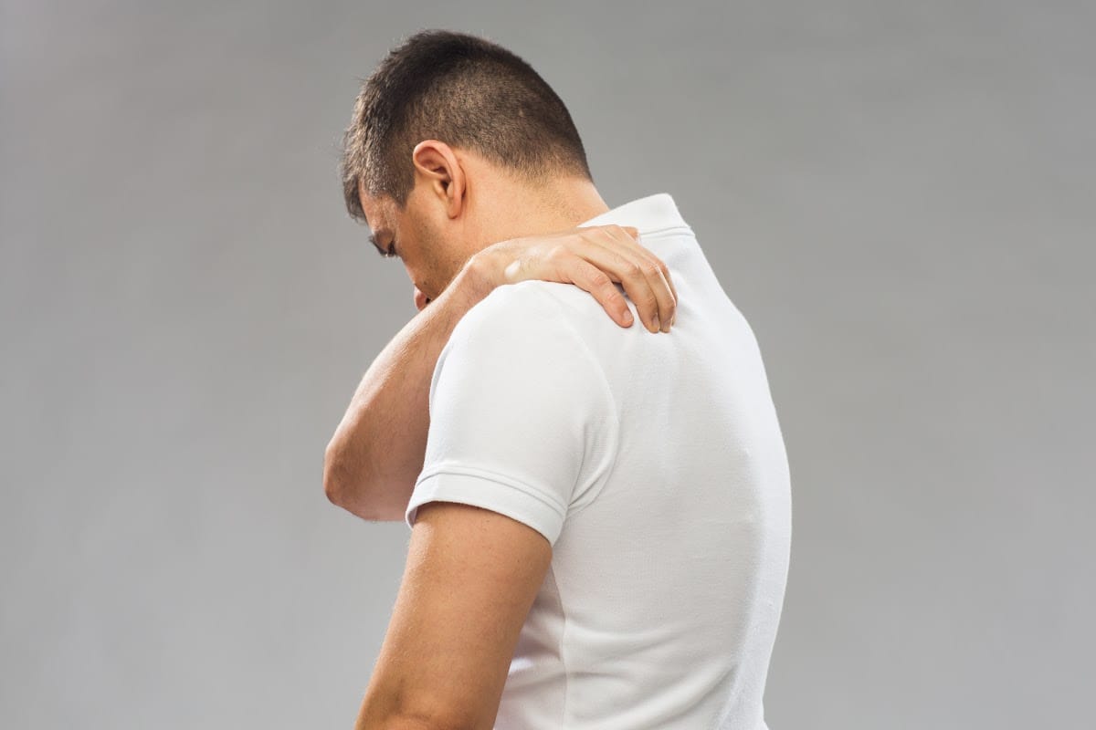 man holding upper back in pain